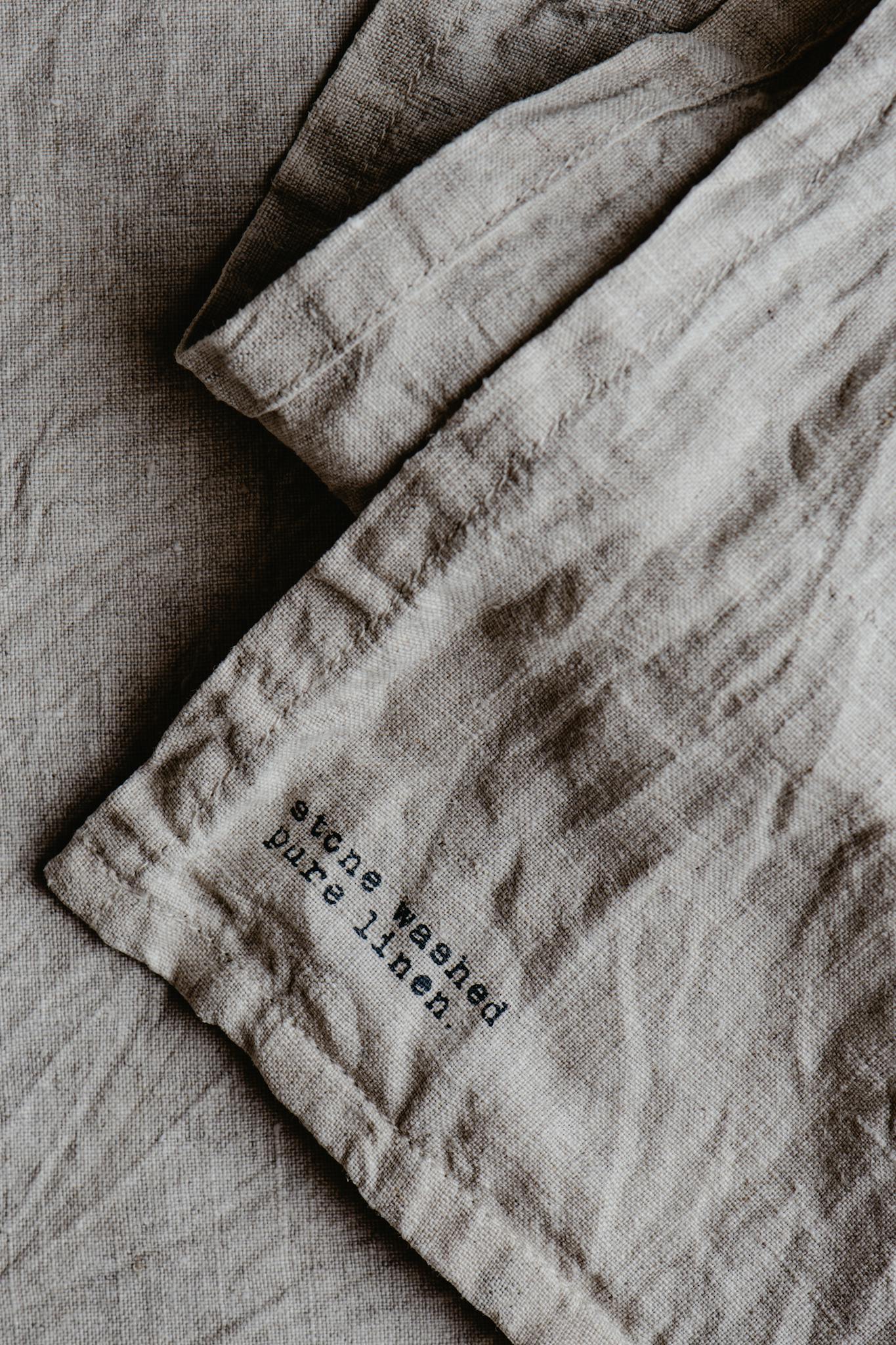Detailed close-up of stone washed pure linen fabric with texture and folds.