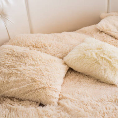 Beige fluffy pillows on the bed in cozy bedroom, interior design concept.