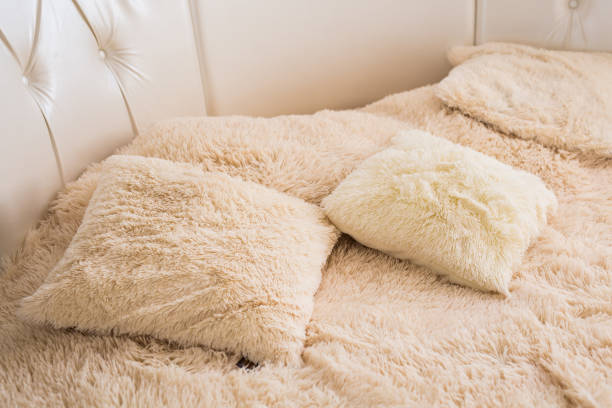 Beige fluffy pillows on the bed in cozy bedroom, interior design concept.