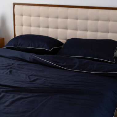 Dark blue cotton bedding on the bed, pillows and blanket